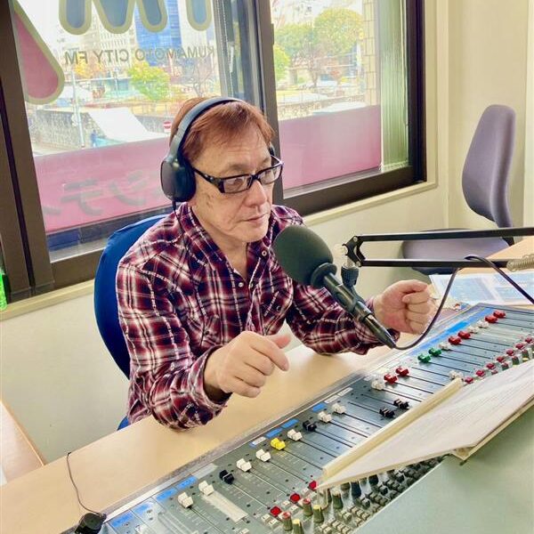 パーソナリティ画像　やまちゅう師匠です。ミキサー卓に座っている様子です。